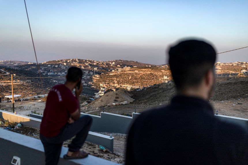 Palestinian men watch Israeli soldiers from the roof of one of the Palestinian homes besieged by Israeli settlers in Qusra on August 18.