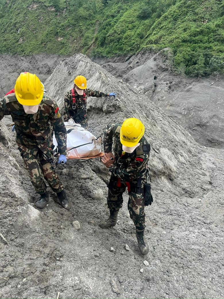 Army personnel carry the body of a victim near the tunnel of the Trishuli 3A Hydropower Project.