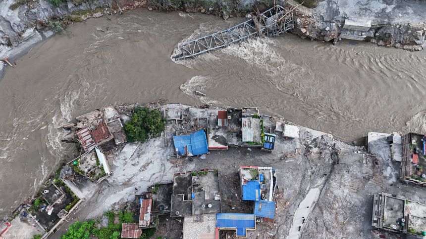 An aerial view shows a collapsed bridge and damaged settlements debris and mud covering an area following flash floods on August 28, in DeviGhat village, Nepal.
